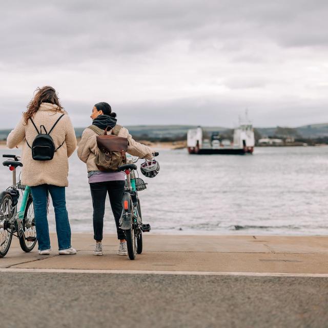 two women with Beryl bikes looking at the Studland chain ferry